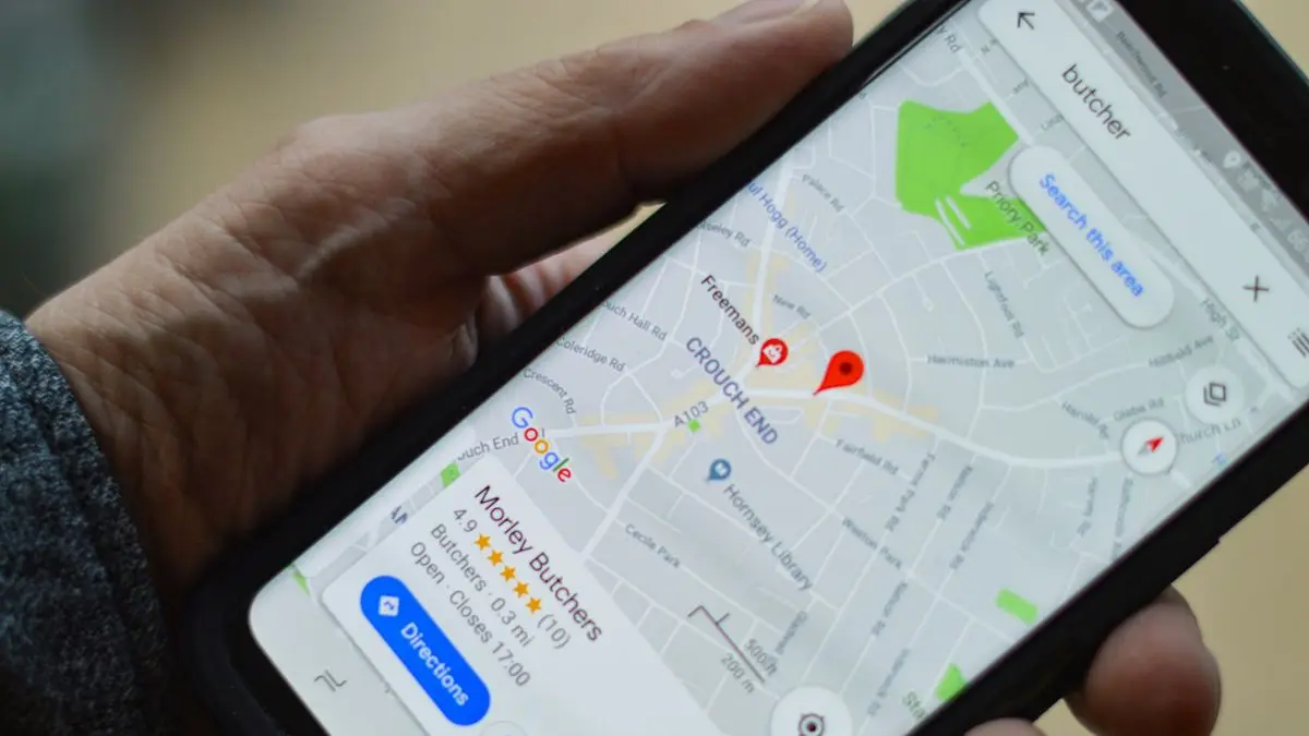 Hand hält ein Smartphone mit Google Maps: ein Betrieb mit Sternebewertung ist auf der Karte markiert