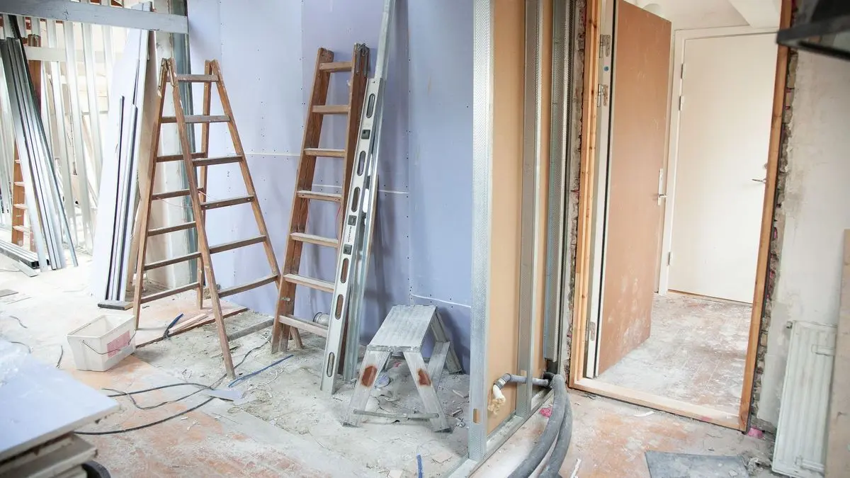 Leere Trockenbau-Baustelle mit zwei Holzleitern, Wasserwaage, Metallprofilen und Gipsplatten, niemand ist zu sehen