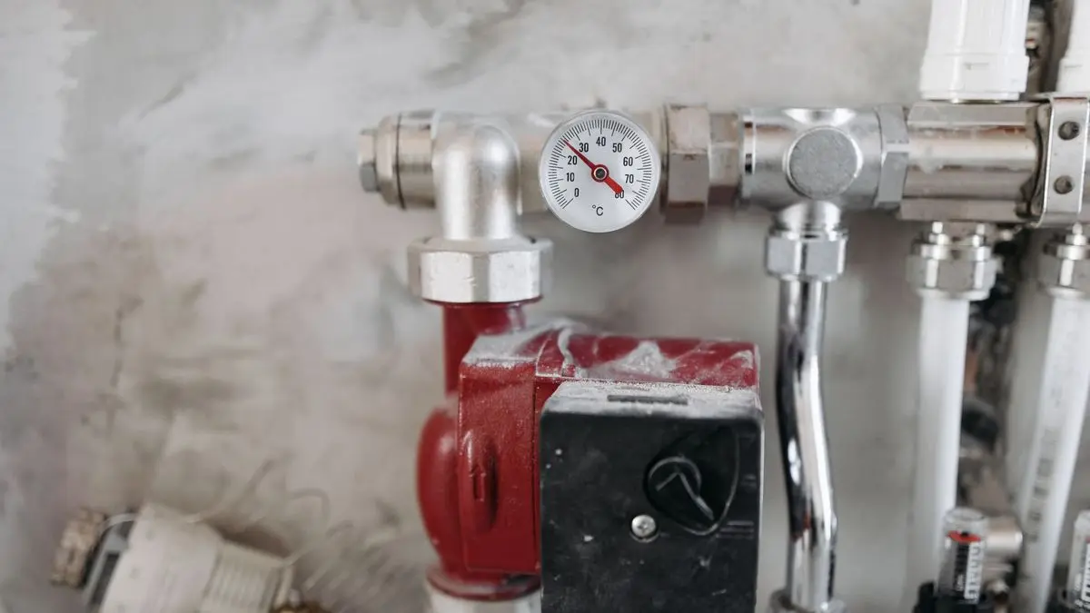 Heizkreisverteiler mit roter Umwälzpumpe, Thermometer und verchromten Rohren an einer Wand